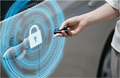 A close-up of a hand with a car key fob pointing at a digital blue security lock icon on a car door for theft protection technology.